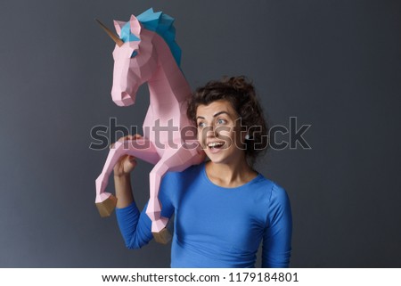 Portrait of a beautiful brunette girl in a blue blouse that keeps a unicorn