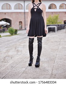 Portrait Of A Beautiful Brunette Woman. The Model Is Wearing A Short Black Skirt And Knee High Leather Boots. High Heels