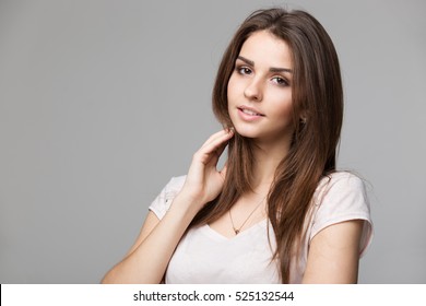Portrait of beautiful brunette woman with natural make-up, on grey background