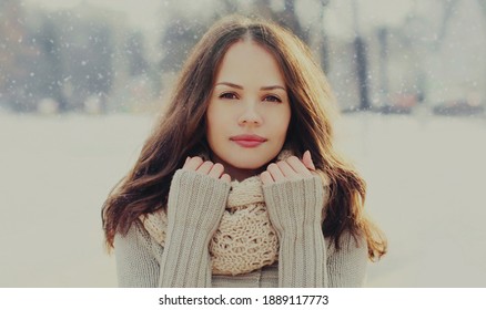 Portrait of beautiful brunette young woman wearing a scarf in winter over a snowflakes background