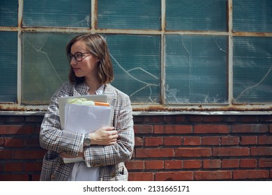 Portrait of beautiful business woman in blazer standing in front of old new yorker building while holding some paperwork and documents ready for a professional and important meeting in town. Vintage