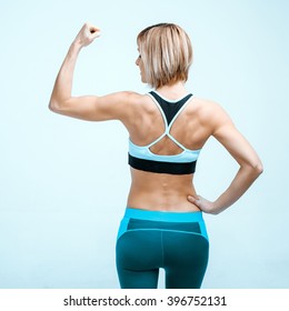 Portrait Of Beautiful Caucasian Blonde Sporty Woman. Young Athlete Showing Strong Arm And Back