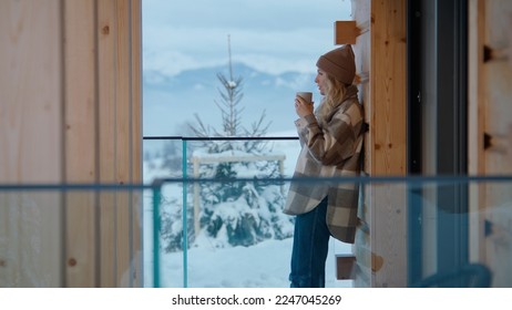 Portrait of beautiful Caucasian female enjoying the view of snowy mountains while having a morning coffee - Powered by Shutterstock