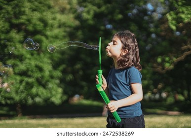 Portrait of a beautiful caucasian girl blows soap bubbles standing in the park - Powered by Shutterstock