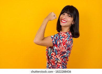 Portrait of beautiful Caucasian woman isolated over yellow background,  showing muscles after workout. Health and strength concept. - Shutterstock ID 1822288436