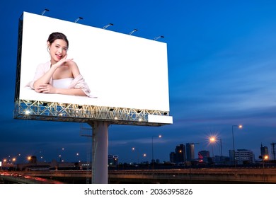 Retrato de una encantadora joven mujer asiática posando en la cara y sentada con anuncios de mesa blanca en una valla publicitaria en blanco para afiches publicitarios al aire libre o carteles en blanco para publicidad.