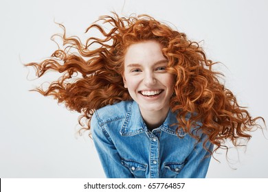 Portrait of beautiful cheerful redhead girl with flying curly hair smiling laughing looking at camera over white background.