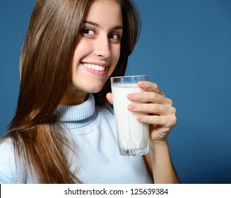 Portrait Of Beautiful Cheerful Teen Girl Drinking Milk Over Blue Background