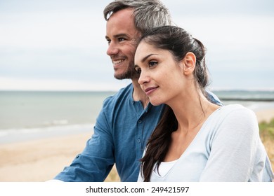 Portrait of a beautiful couple at the beach wearing casual clothes and looking at the ocean