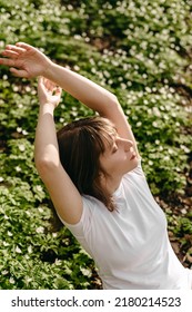 The Portrait Of Beautiful Cute Woman No Makeup In White Shirt Laying Down On Green Grass With White Flowers. Sunny Summer Day, Wild Nature, Mood Vacation, Relax. Top View Of Girl. Be Free, Love Forest