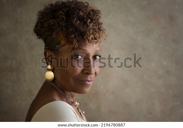 Portrait of a beautiful elderly 70-year-old\
African-American grandma spokesperson looking back over shoulder\
with ad or copy space for your\
ad