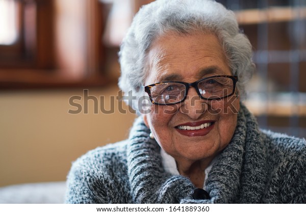 Portrait beautiful elderly woman smiling\
sitting on sofa at home enjoying\
retirement