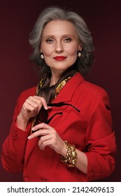 Portrait of a beautiful elderly womanin a red jacket with accessories and classic makeup and gray hair.