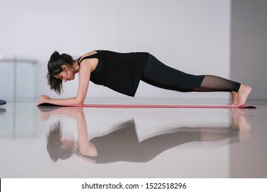 Portrait Of A Beautiful, Elegant And Attractive Indian Asian Woman Doing A Plank To Strengthen Her Core On An Exercise Mat In The Gym Or At Home During The Morning. 