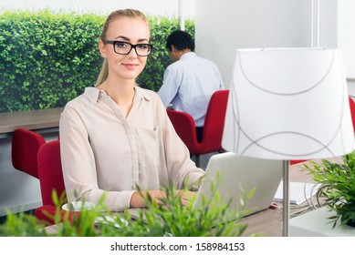 Portrait Of Beautiful Environmentalist With Laptop At Desk Sitting In A Hot Desk Office