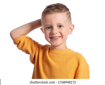 Portrait Of A Beautiful European Boy 6 Years Old On A White Background. The Blue-eyed Child Is Smiling Broadly, His Hand Behind His Head. Children's Emotions. 