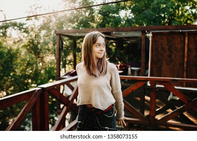 Portrait Of Beautiful European Female Looking Away And Being Equipped Before Zip Lining On A Zipline Platform.