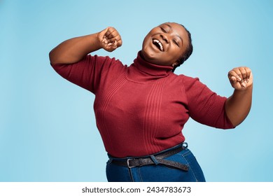 Portrait of beautiful, excited, body positive African American woman wearing casual outfit, dancing isolated on blue background. Happy young female having fun. Concept of positive lifestyle - Powered by Shutterstock