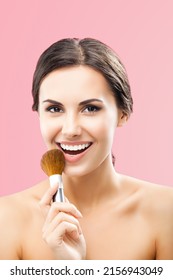 Portrait of beautiful excited smiling woman holding in hand, showing, giving cosmetics brush, isolated over rose pink color background. Happy brunette girl at beauty treatment, visage, makeup concept.