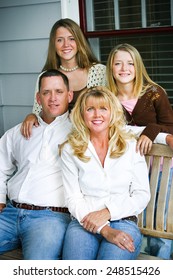 Portrait Of A Beautiful Family Sitting On Their Front Porch Swing.  