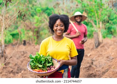 portrait of a beautiful female african farmer carrying basket of vegetable