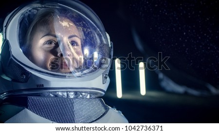 Portrait of the Beautiful Female Astronaut on the Alien Planet. Earth Reflection on her Helmet. In the Background Living Habitat. Space Travel, Exploration and Solar System Colonization Concept.