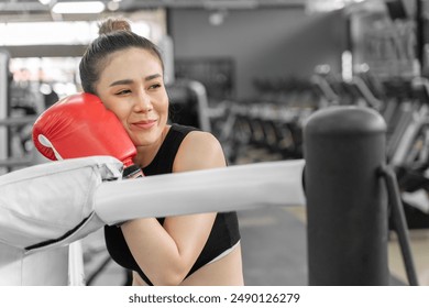 Portrait of a beautiful female boxer resting at the boxing ring in a gym - Powered by Shutterstock