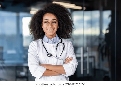 Portrait of beautiful female doctor inside office of modern clinic, female doctor smiling and looking at camera with crossed arms, female worker with stethoscope and white medical coat at workplace. - Powered by Shutterstock