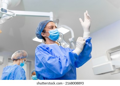 Portrait of beautiful female doctor surgeon putting on medical gloves standing in operation room. Surgeon at modern operating room - Powered by Shutterstock