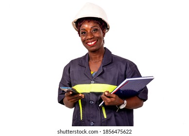 Portrait Of A Beautiful Female Engineer Wearing Work Uniform And White Hard Hat Holding A Mobile Phone And A Notebook While Smiling.