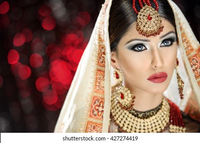 Portrait of a beautiful female model in classic indian asian bridal outfit looking sophisticated and classy with makeup and jewellery