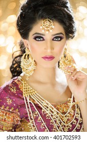 Portrait of a beautiful female model in ethnic indian bridal costume with heavy jewellery and traditional makeup