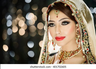 Portrait of a beautiful female model in ethnic indian bridal costume with heavy jewellery and traditional makeup