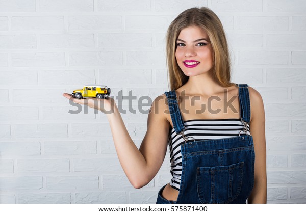 portrait of beautiful female model in jeans and toy\
car in in her hands