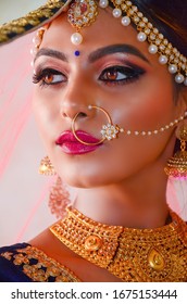 Portrait of a beautiful female model in traditional ethnic Indian bride costume with heavy jewellery and makeup