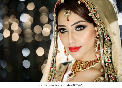 Portrait of a beautiful female model in traditional ethnic Indian Pakistani bride costume with heavy jewellery and makeup