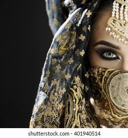 Portrait of a beautiful female model wearing a turban and veil in heavy eye makeup and jewellery