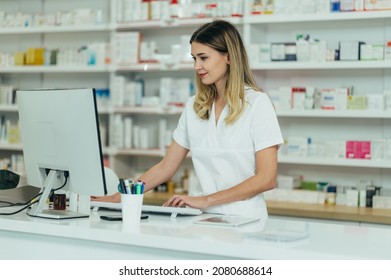 Portrait of a beautiful female pharmacist working in a pharmacy and using a computer - Powered by Shutterstock