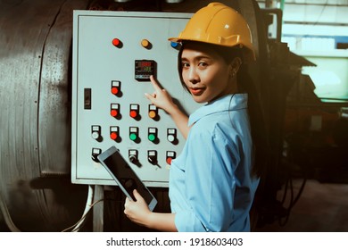 Portrait beautiful female technician wears a yellow helmet, controls the buttons, the boiler control system, notes the pressure on the laptop and other safety equipment for industrial safety. - Powered by Shutterstock