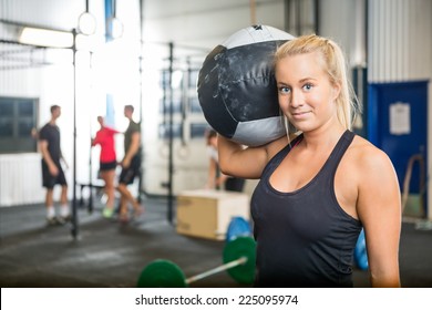 Portrait Of Beautiful Fit Woman Carrying Medicine Ball At Crossfit Gym