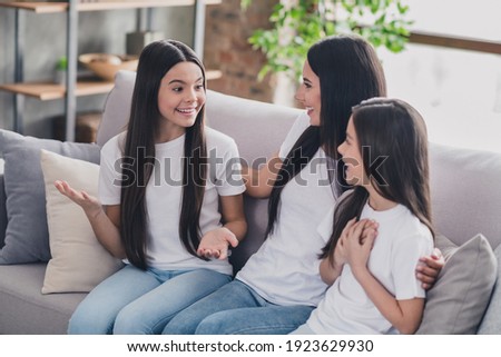 Portrait of beautiful funny cheerful girls friends communicating spending day sitting on divan at house flat apartment indoors