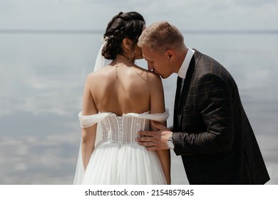 portrait of a beautiful, gentle and happy bride and groom. the man gently kisses the woman's shoulder. love, romance and passion in a relationship. wedding ceremony outdoors. High quality photo