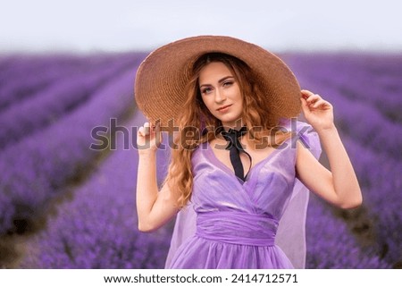 Portrait of a beautiful girl in a big hat in Provence on the background of a lavender field