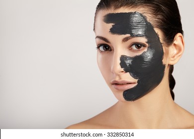 Portrait Of A Beautiful Girl With A Black Mask Of Clay On Her Face.