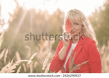 portrait of a beautiful girl, blonde of Slavic appearance with red lipstick with a rowan wreath on her head against the backdrop of nature in autumn. High quality photo