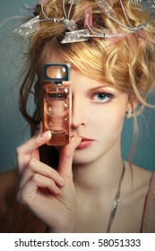 Portrait of the beautiful girl with a bottle of perfume about her face