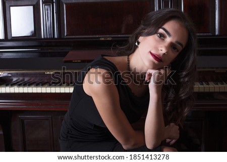 Portrait of beautiful girl with dreamy look in front of piano keyboard