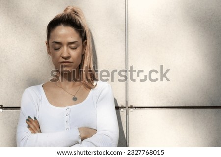Portrait of a beautiful girl with eyes closed infront of modern building facade.