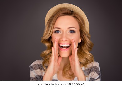 Portrait of beautiful girl in hat holding hand near face and making announcement