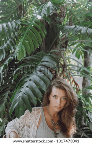 Portrait of a beautiful girl  with long hair  in the leaves of a palm tree in an Asian countryside